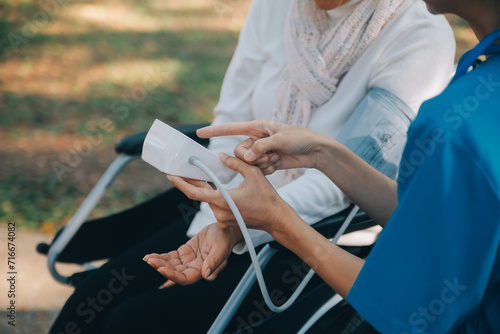 nurse with elderly man in wheelchair at park