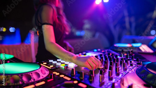Close em mão feminina, manuseando os botões do controlador de dj, durante uma festa com muitas luzes coloridas.