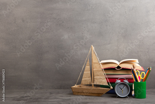 Education is a journey concept, toy boat and books on the table, inspiration for a writing a fairy tale. Elementary school supplies