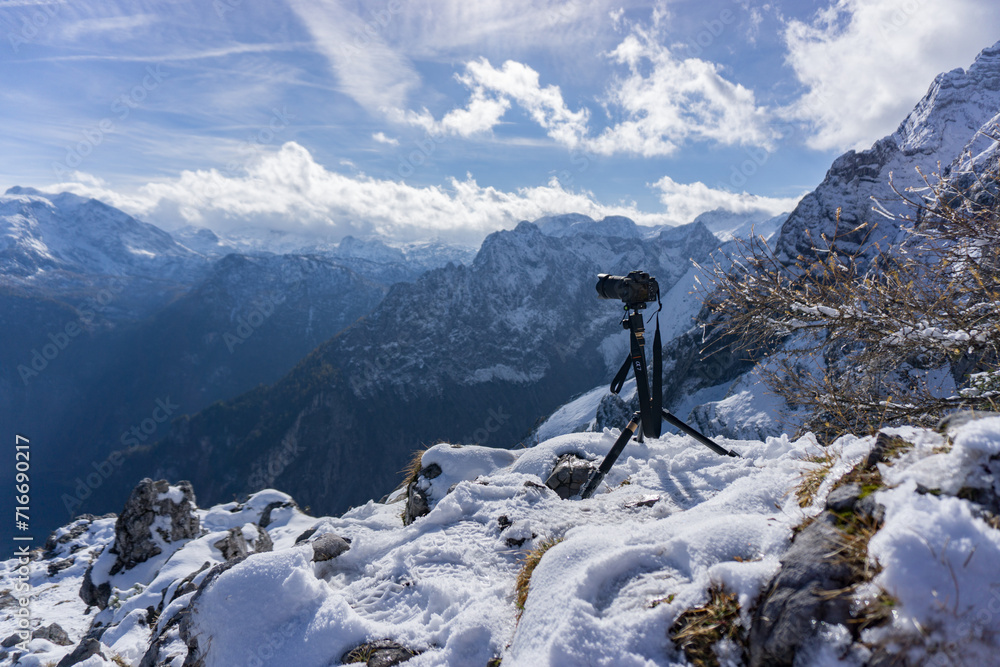 A camera on a tripod poised to capture the beauty of a snow-capped mountain range under a bright sky. A camera on a tripod poised to capture the beauty of a snow-capped mountain range under a bright sky.