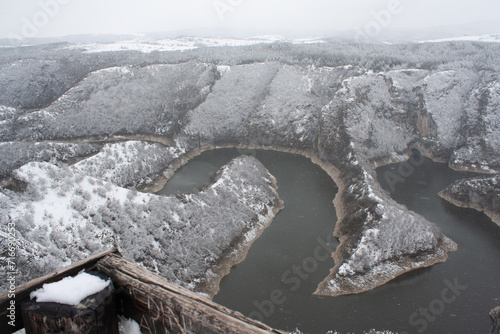 A winding river cutting through a snowy landscape viewed from an overlook.