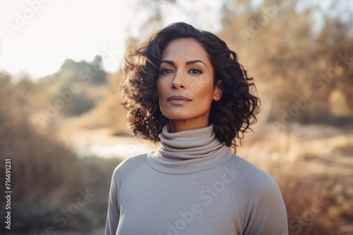 Portrait of a tender indian woman in her 50s wearing a classic turtleneck sweater against a serene meditation room. AI Generation
