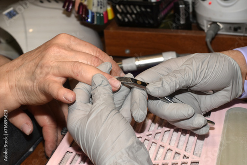 A manicurist works with tongs.