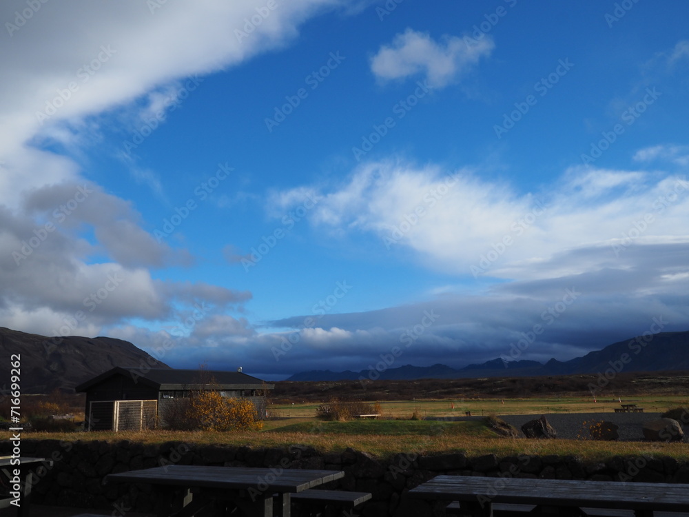 Chill out area near the Geysir, Iceland, a gorgeous view of plateau, mountains under a bright blue sky and white clouds