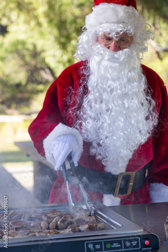 santa claus cooking lamb chops and sausages on a bbq in a park photo