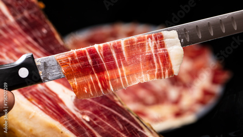 Slika na platnu Preparing a plate of Spanish cured acorn fed Iberian ham cut with a knife for tasting at an event