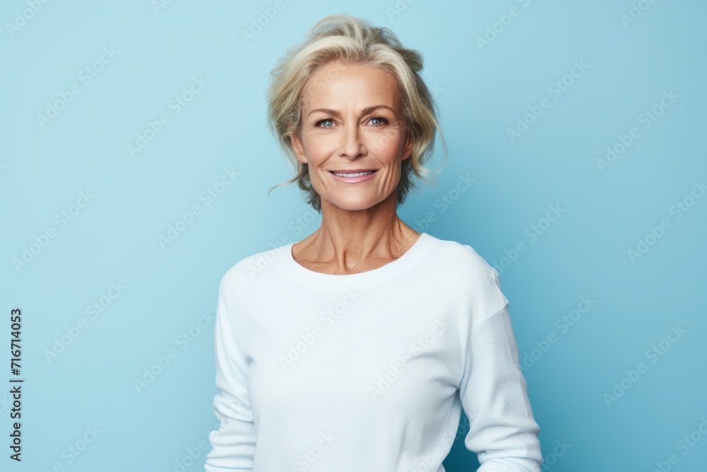 Portrait of a merry woman in her 50s sporting a long-sleeved thermal undershirt against a pastel blue background. AI Generation Portrait of a merry woman in her 50s sporting a long-sleeved thermal undershirt against a pastel blue background. AI Generation