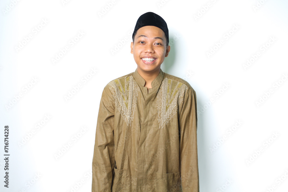 pleased asian muslim man smiling at camera wearing islamic clothes isolated on white background