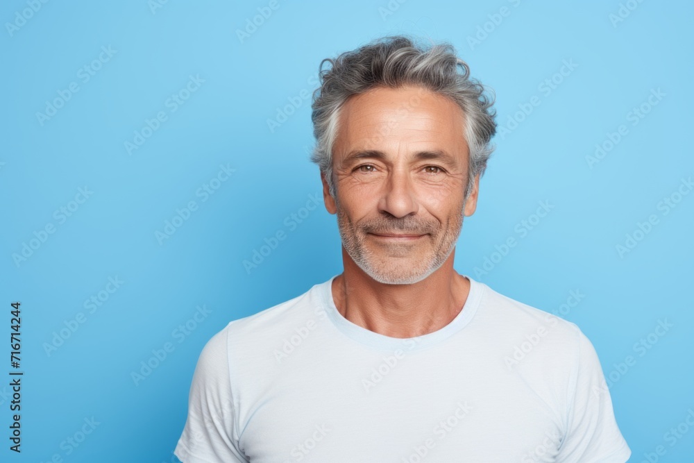 Portrait of a tender man in his 50s dressed in a casual t-shirt against a pastel blue background. AI Generation Portrait of a tender man in his 50s dressed in a casual t-shirt against a pastel blue background. AI Generation