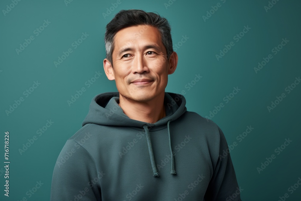 Obraz premium Portrait of a tender asian man in his 40s wearing a thermal fleece pullover against a pastel teal background. AI Generation