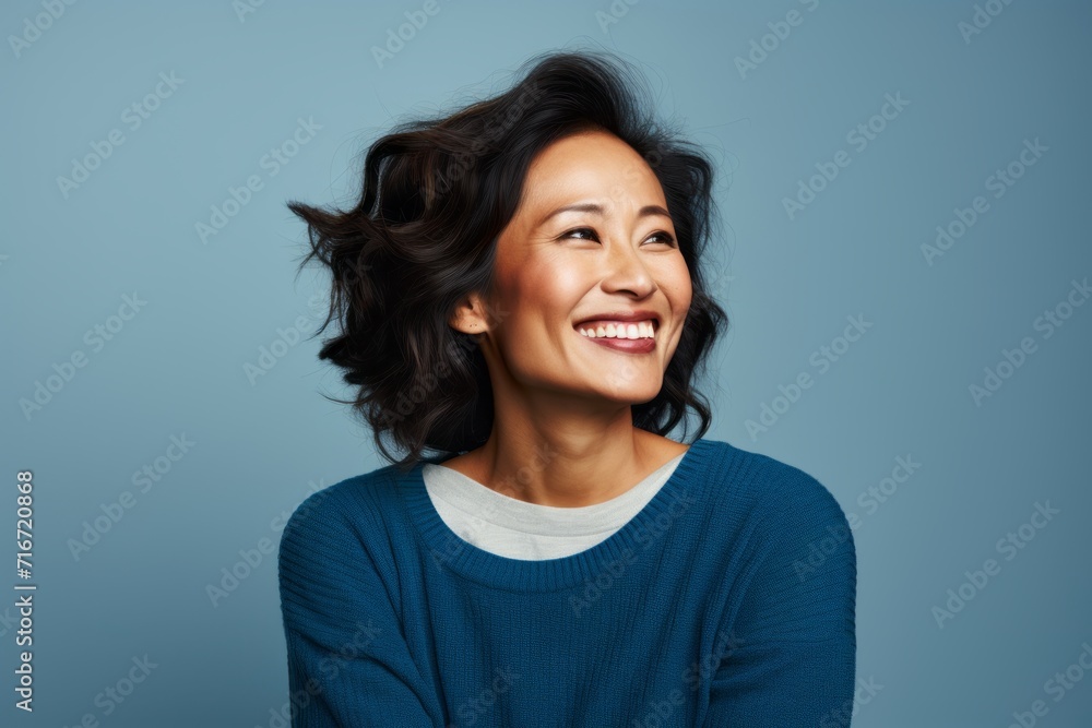 Portrait of a cheerful asian woman in her 40s wearing a cozy sweater against a soft blue background. AI Generation Portrait of a cheerful asian woman in her 40s wearing a cozy sweater against a soft blue background. AI Generation