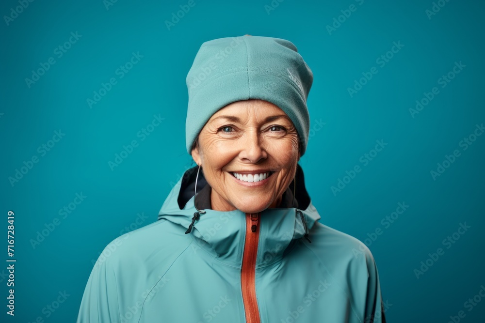 Portrait of a satisfied woman in her 60s wearing a windproof softshell against a soft teal background. AI Generation Portrait of a satisfied woman in her 60s wearing a windproof softshell against a soft teal background. AI Generation