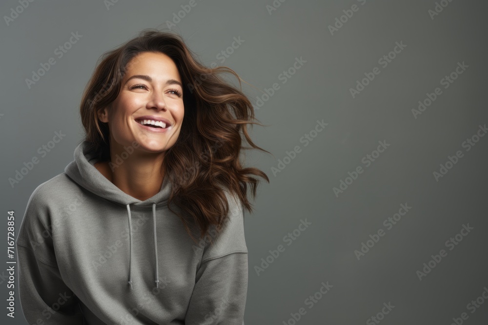 Portrait of a blissful woman in her 30s dressed in a comfy fleece pullover against a soft gray background. AI Generation