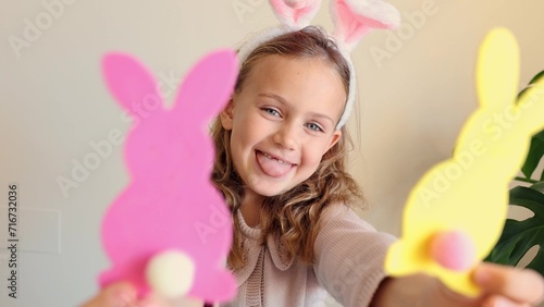 Close up hands child girl holds paper colored garland Easter bunny pompons. Excited emotional children. Rabbit years crafts for Easter party at home. Holiday Art Activity Kid. creativity hobby DIY photo