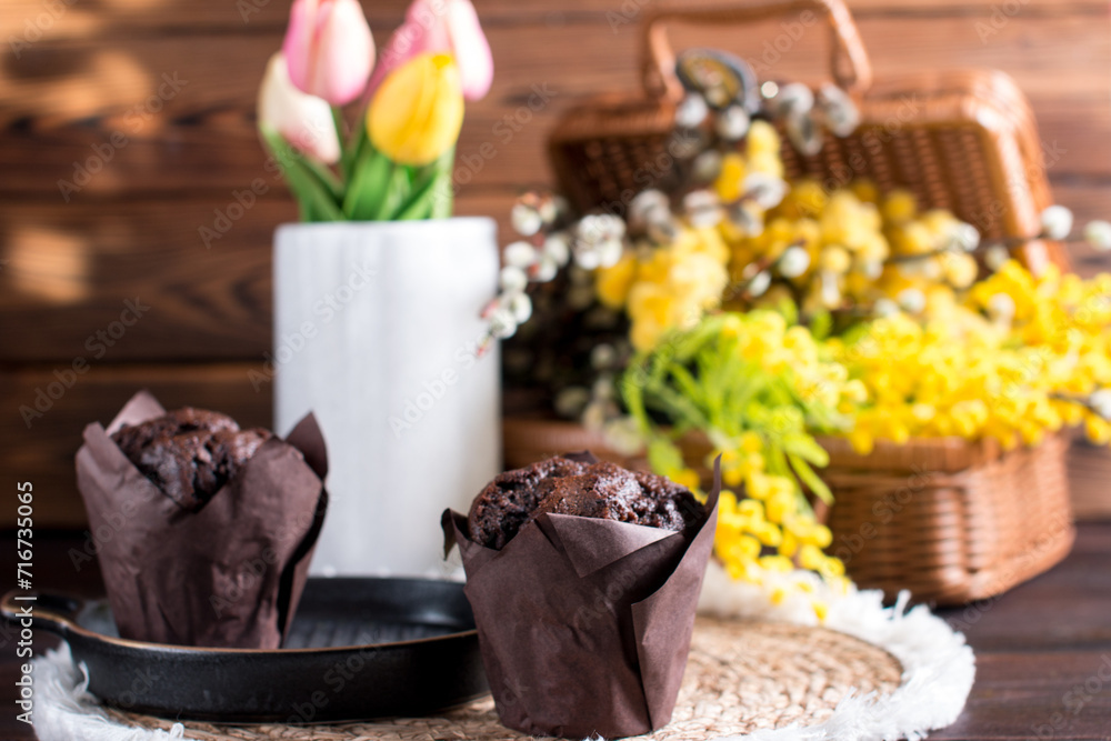 Cupcake muffin with chocolate on a white background with a bouquet of mimosa. Congratulations on International Women's Day, postcard