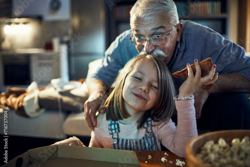 Grandfather and granddaughter watching tv in the living room at home photo