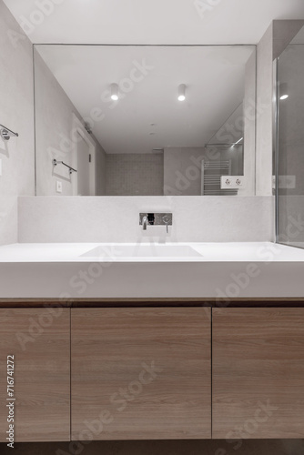 A modern design bathroom with an integrated mirror that runs along the entire wall  a straight one-piece porcelain sink