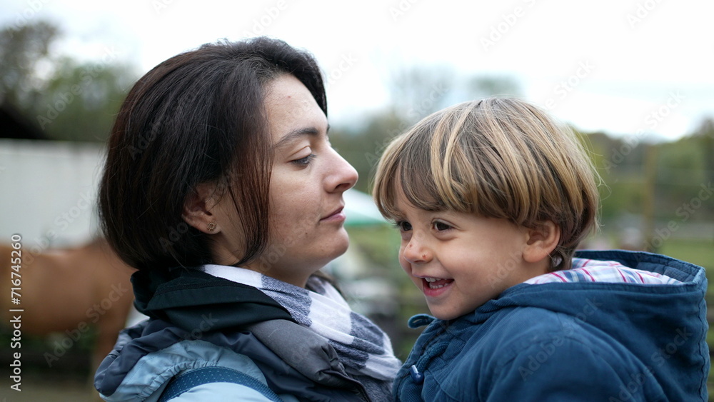 Mother and child bonding outside in authentic real life affectionate moment kissing on the lips and dancing side to side. Mom holding son in arms during fall season Mother and child bonding outside in authentic real life affectionate moment kissing on the lips and dancing side to side. Mom holding son in arms during fall season