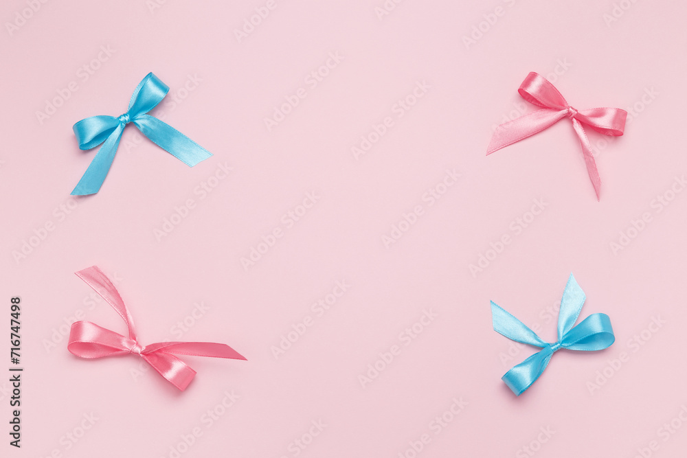 Multicolored bows on pink background. Top view, copy space
