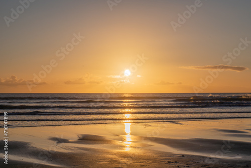 Fototapeta Naklejka Na Ścianę i Meble -  Mesmerizing beach sunset with vibrant colors, tranquil waves, and coastal beauty, ideal for relaxation, travel, golden skies