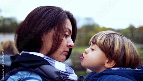 Mother and child peck kiss in authentic caring parent and child relationship. mom holding small son in arms