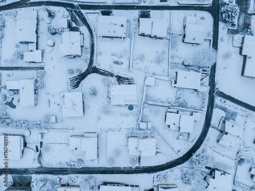 Aerial view of suburban neighborhood with snow covered roofs and streets. Small town in winter time in Switzerland, Europe.