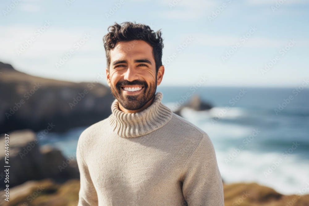 Portrait of a grinning indian man in his 20s wearing a classic turtleneck sweater against a serene seaside background. AI Generation Portrait of a grinning indian man in his 20s wearing a classic turtleneck sweater against a serene seaside background. AI Generation
