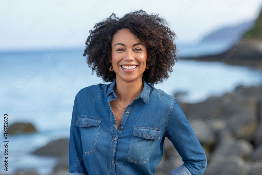 Portrait of a cheerful afro-american woman in her 40s sporting a versatile denim shirt against a peaceful tide pool background. AI Generation Portrait of a cheerful afro-american woman in her 40s sporting a versatile denim shirt against a peaceful tide pool background. AI Generation