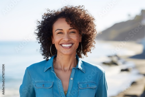 Portrait of a cheerful afro-american woman in her 40s sporting a versatile denim shirt against a peaceful tide pool background. AI Generation