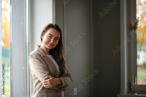 A smiling businesswoman. A small business entrepreneur stands near the window in her office © Айман Дайрабаева