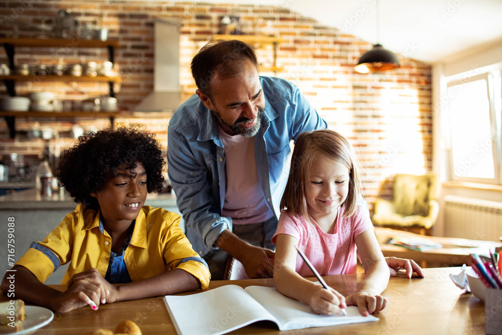 Father helping his diverse children with homework at home Father helping his diverse children with homework at home