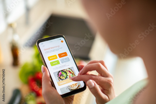 Woman using a meal planning app on smartphone in kitchen