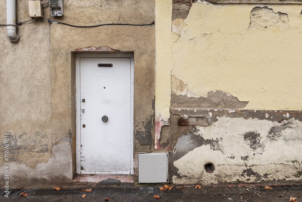 White metal door on the facade of a very deteriorated painted White metal door on the facade of a very deteriorated painted