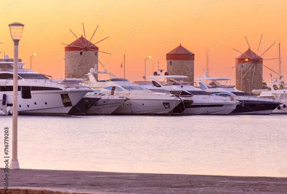 Fototapeta premium Old windmills in Rhodes against the background of the dawn sky.