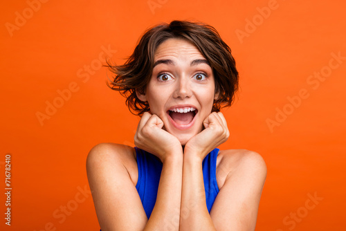 Portrait of gorgeous cheerful person arms touch cheekbones open mouth unbelievable isolated on orange color background