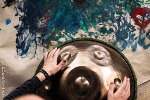 A musician's hand playing the handpan with other people. 