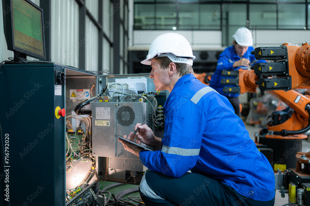 Technician working on the electrical control cabinet of robotic arm, Robotic arms industrial background Technician working on the electrical control cabinet of robotic arm, Robotic arms industrial background