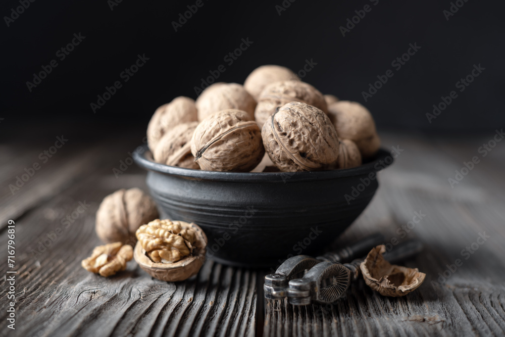 Walnut nuts with a vintage silver nut cracker on wooden table close up. Food photography