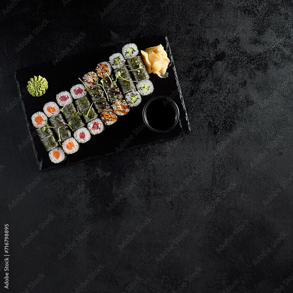 Top view of an assorted hosomaki sushi set with salmon, tuna, eel, and cucumber on a black slate Top view of an assorted hosomaki sushi set with salmon, tuna, eel, and cucumber on a black slate