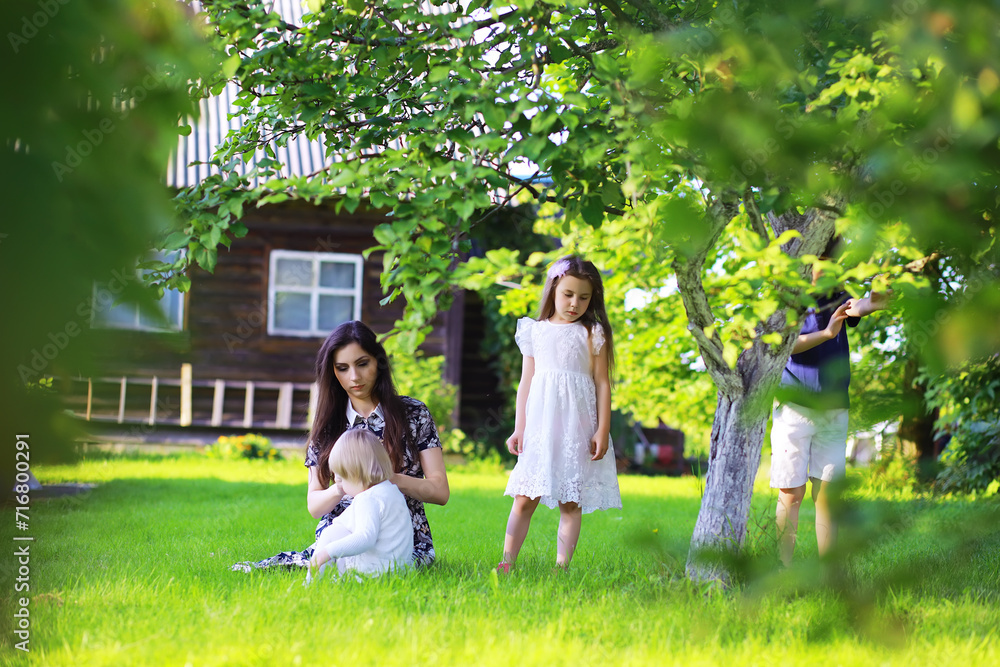 Fototapeta premium Young large family on a summer morning walk. Beautiful mother with children is playing in the park.