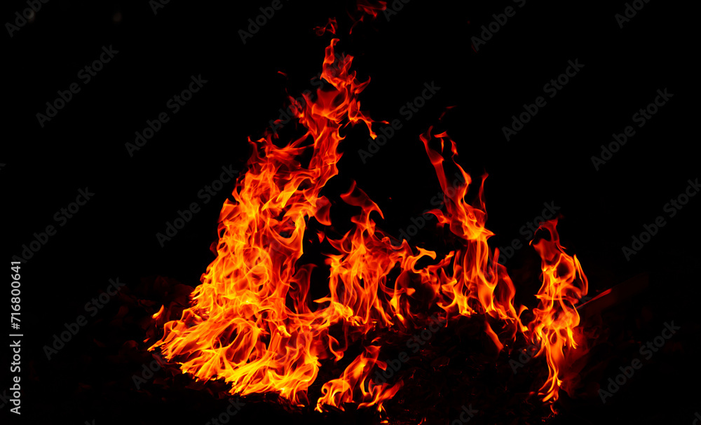 Bright flames rising and moving at dark nigh in blurred background.Orange fire flames.Burning red hot sparks rise, Fiery orange glowing flying particles. Bright flames rising and moving at dark nigh in blurred background.Orange fire flames.Burning red hot sparks rise, Fiery orange glowing flying particles.
