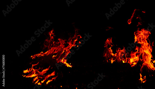 Bright flames rising and moving at dark nigh in blurred background.Orange fire flames.Burning red hot sparks rise, Fiery orange glowing flying particles.