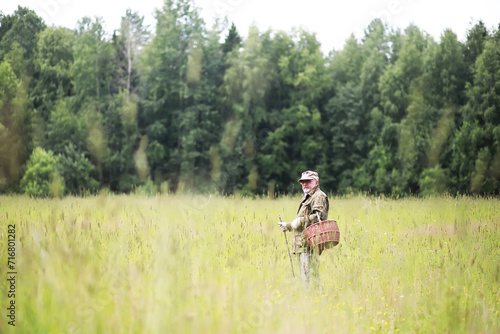 A man walks across the field into the forest for mushrooms. The mushroom picker goes to the forest. © alexkich