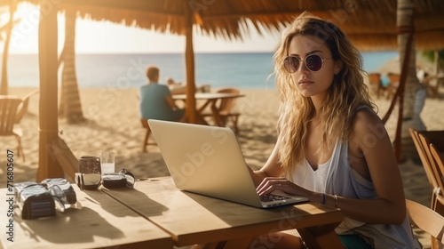 Caucasian woman working with laptop on beach.