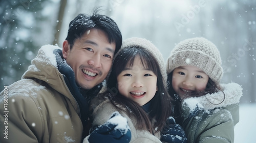 Asian family wearing coats playing in the snow.