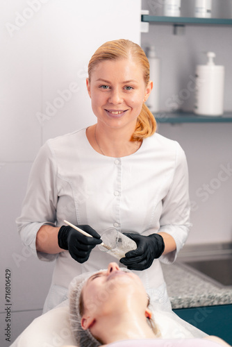 cosmetologist in gloves applies a mask to the client's décolleté and neck with a brush skin care