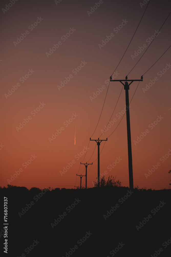 Silhouettes of electricity poles at sunset. Renewable energy