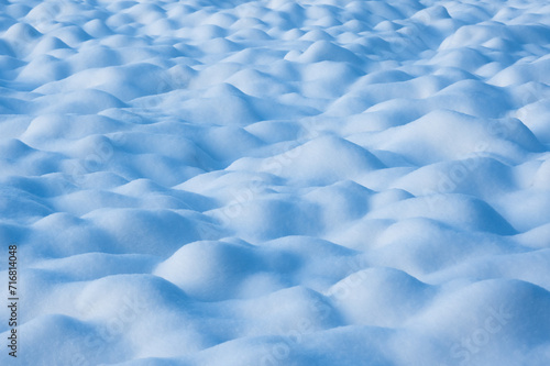 Abstract winter background from blue snow waves on snowy field