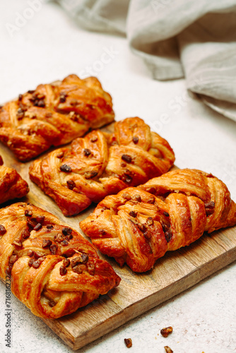 freshly baked croissants with pecans, on a wooden board, light background