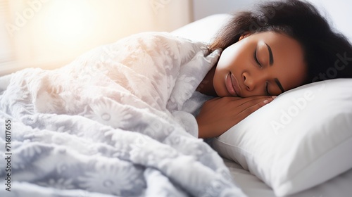 Pretty African-American woman sleeps calmly under blanket on soft bed at home closeup